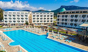 Outdoor hotel pool area between resort buildings with sun loungers and umbrellas.