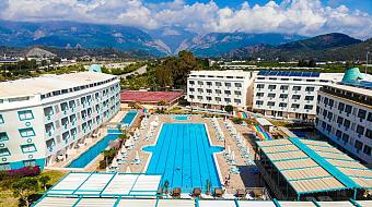 Wide view of the resort courtyard with a large outdoor swimming pool and surrounding buildings.