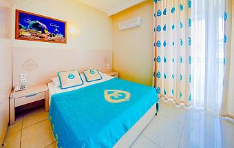 Double room with turquoise bedspread, bedside tables, and air-conditioning.