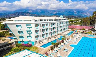 Resort building next to the outdoor pool area with loungers, umbrellas, and courts visible nearby.