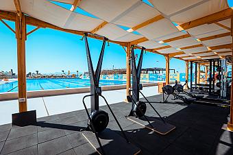 Outdoor-Fitnessstudio am Swimmingpool mit Cardio- und Krafttrainingsgeräten