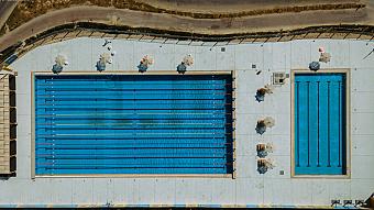 Luftaufnahme von zwei Außenpools mit Schwimmbahnen und Sonnenschirmen