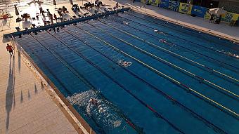 Schwimmer trainieren im Olympiabecken mit Bahnabtrennungen bei Sonnenuntergang
