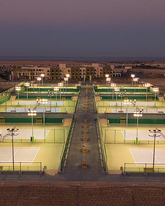 Row of illuminated tennis courts at training camp during evening
