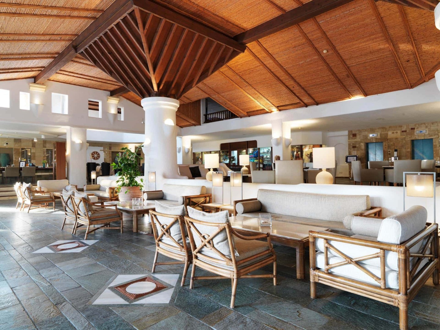 Helle Hotellobby mit Rattanstühlen, weißen Sofas und offenem Design, ideal für Teamtreffen
