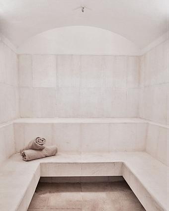 Helles Dampfbad mit gefliesten Bänken und zusammengerollten Handtüchern zur Regeneration der Athleten