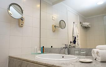 Modernes Badezimmer mit weißen Fliesen, Waschbecken, Spiegel und Bademantel an der Wand