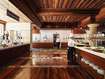 Köche bei der Essenszubereitung im Hotelbuffetrestaurant mit Holzboden und Servicestationen