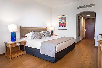 Gemütliches Schlafzimmer mit Kingsize-Bett, Nachttischlampen und minimalistischer Einrichtung für Athleten