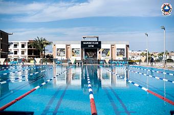 Olympic-size swimming pool with lane dividers in front of Marine Club Gym