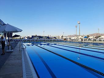 Long Olympic swimming pool with lane markers and surrounding deck for training camp sessions