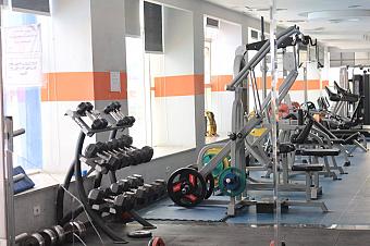 Fitness room with dumbbells, weight machines, and mirrors for training camp conditioning sessions