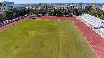 Luftaufnahme eines Leichtathletikstadions mit grünem Rasen und roten Bahnen für das Training
