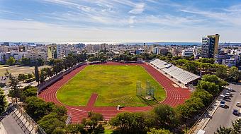 Weitwinkelansicht eines Leichtathletikstadions mit Bahn, Spielfeld und Tribünen in Meeresnähe