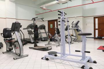 Small gym room with cardio machines and strength equipment on a tiled floor.