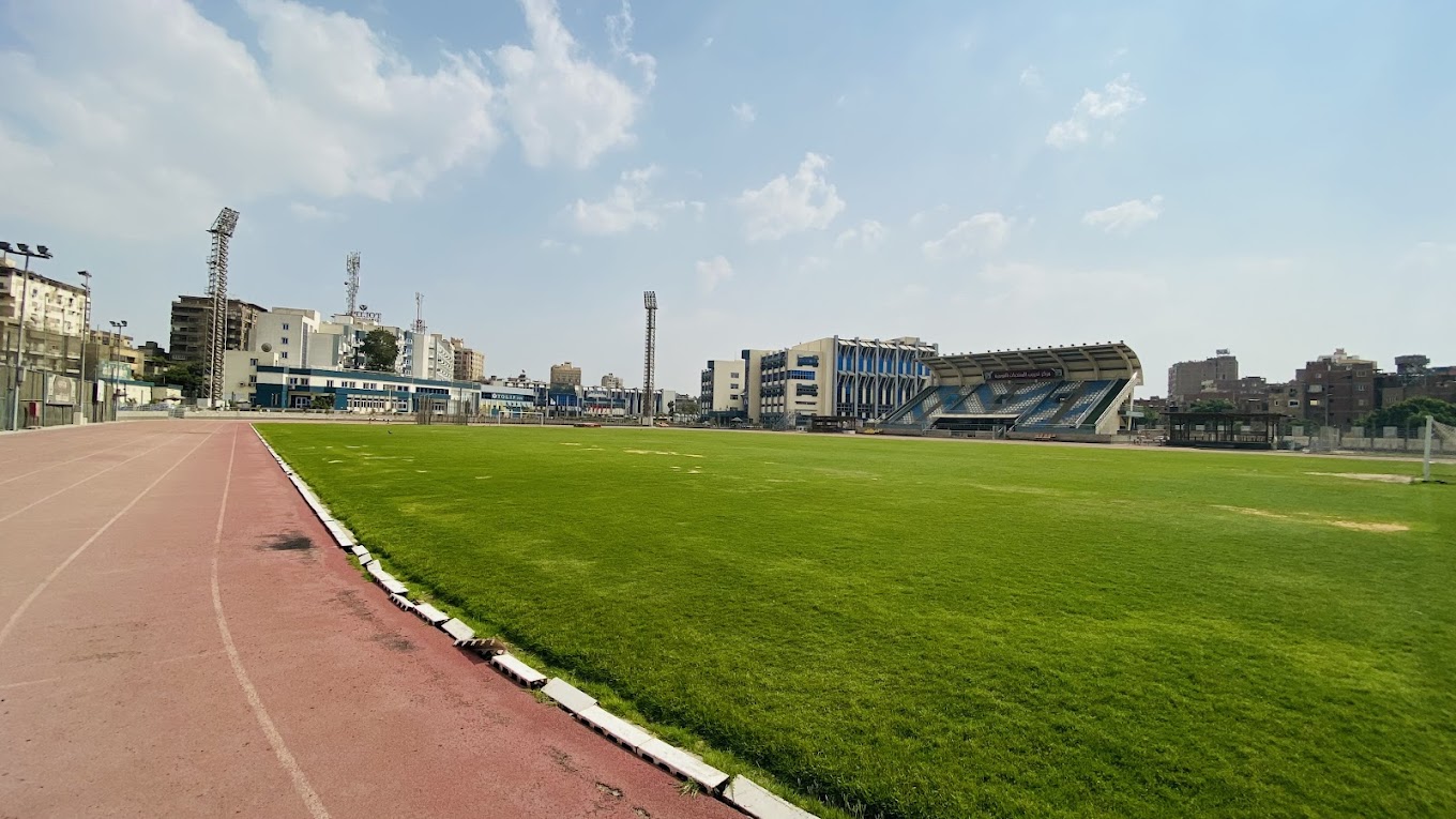 Stadion im Freien mit Leichtathletikbahn, Rasenfeld und überdachter Tribüne.