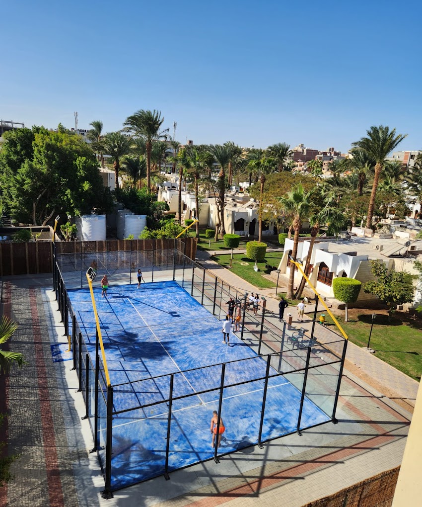 Vue surélevée d'un court de padel extérieur dans l'enceinte du complexe.