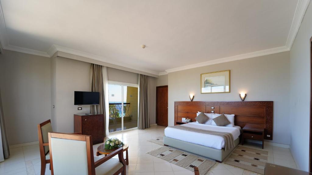 Chambre double lumineuse avec grand lit, coin salon et portes-fenêtres avec vue sur la mer.
