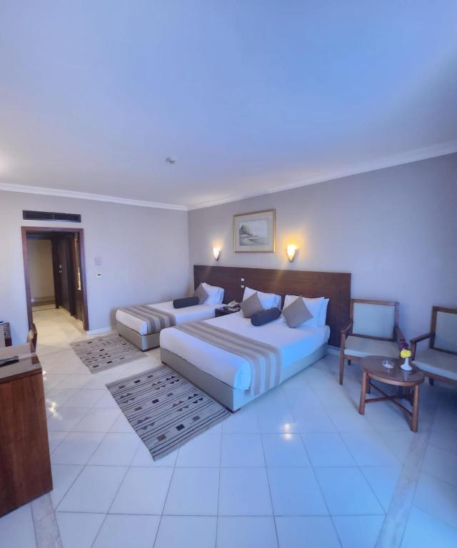 Chambre spacieuse avec lit double, lit simple et coin salon.