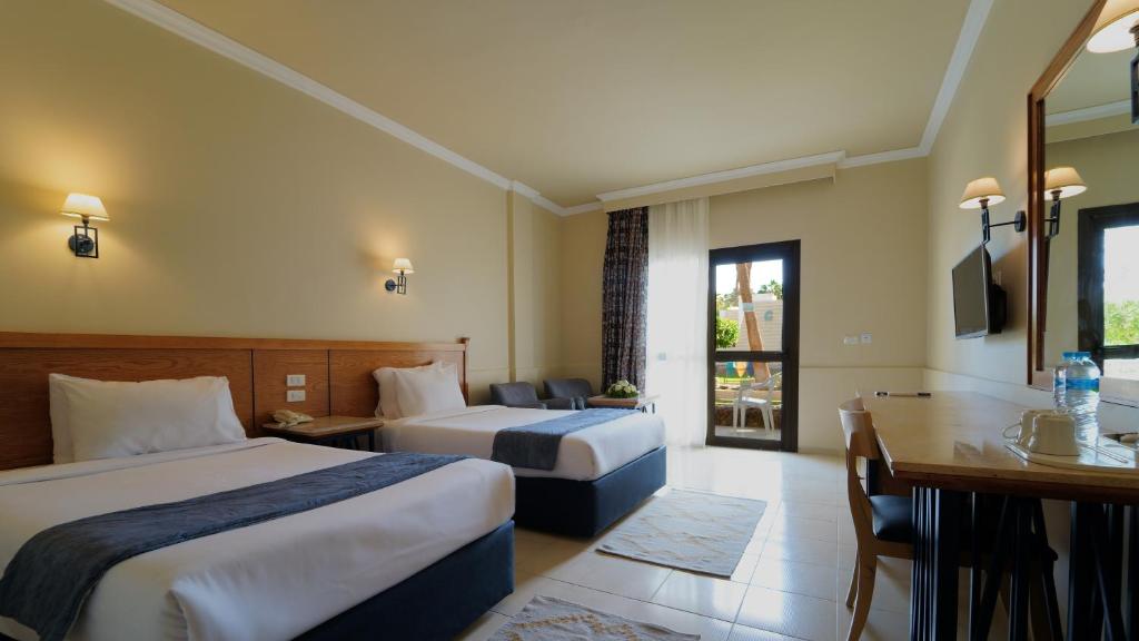 Chambre twin avec deux lits simples, bureau, TV et porte-fenêtre donnant sur le patio.