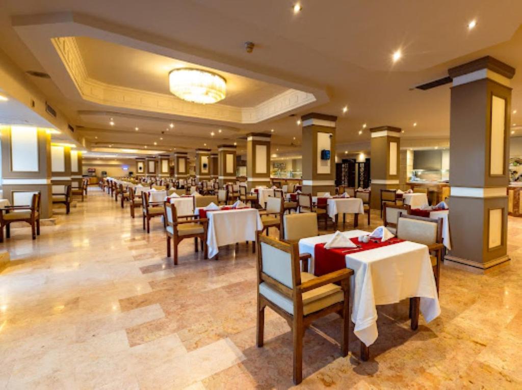 Grande salle de restaurant avec tables dressées et éclairage chaleureux.