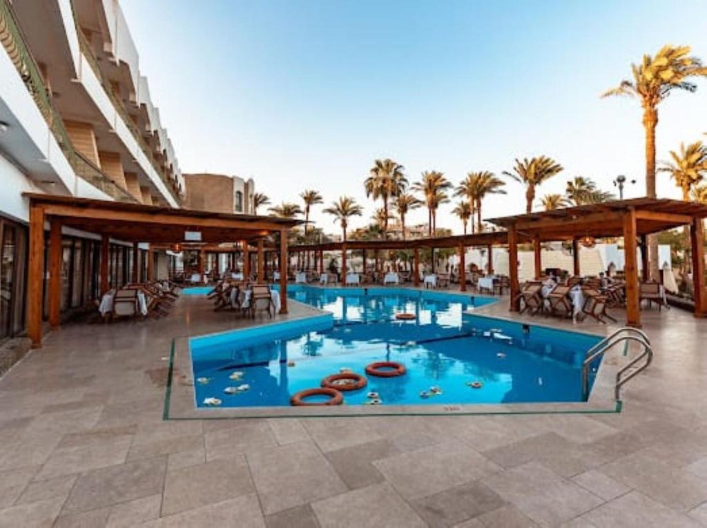 Piscine extérieure avec salon de détente sous des pergolas en bois.