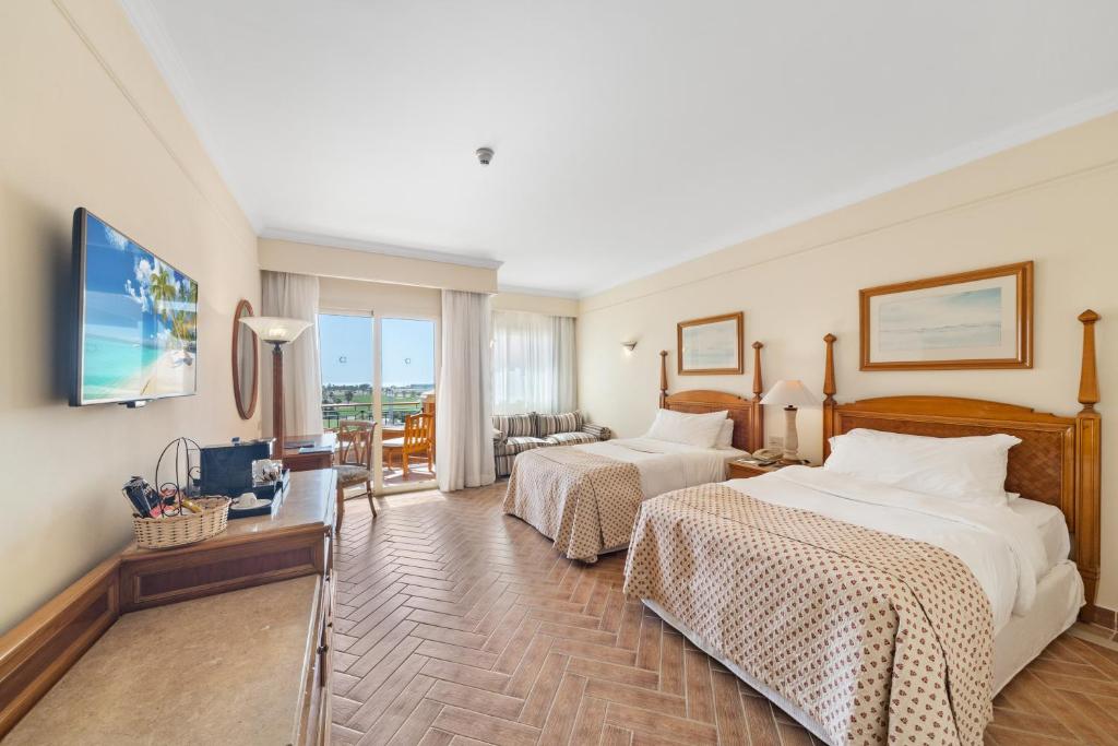 Chambre spacieuse avec lits jumeaux, TV et vue sur balcon pour séjours prolongés.
