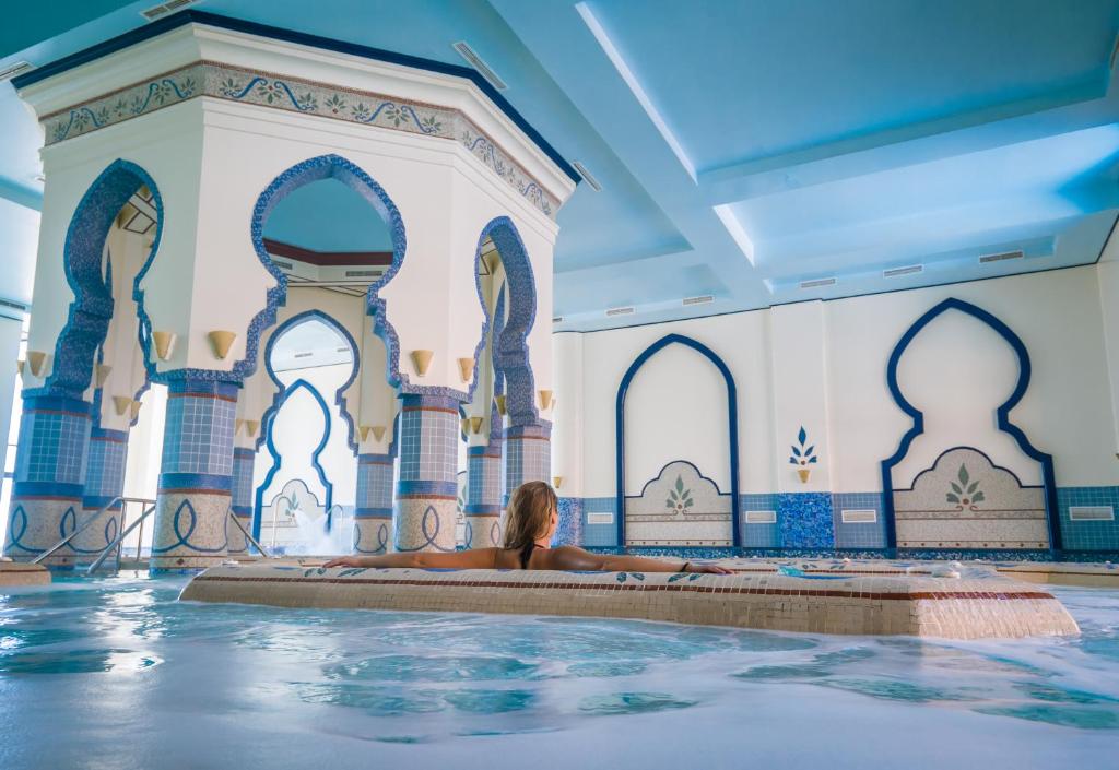 Piscine intérieure avec arches en mosaïque bleue et nageur se relaxant, adaptée pour récupération en stage d'entraînement