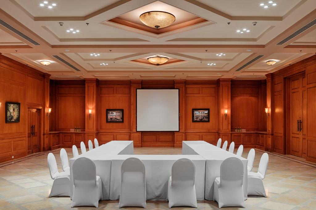 Salle de réunion lambrissée avec tables en U et écran de projection pour briefing d'équipe de stage d'entraînement