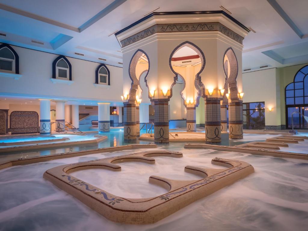 Espace jacuzzi/thalasso intérieur avec eau mousseuse et arches spectaculaires, environnement relaxant de récupération