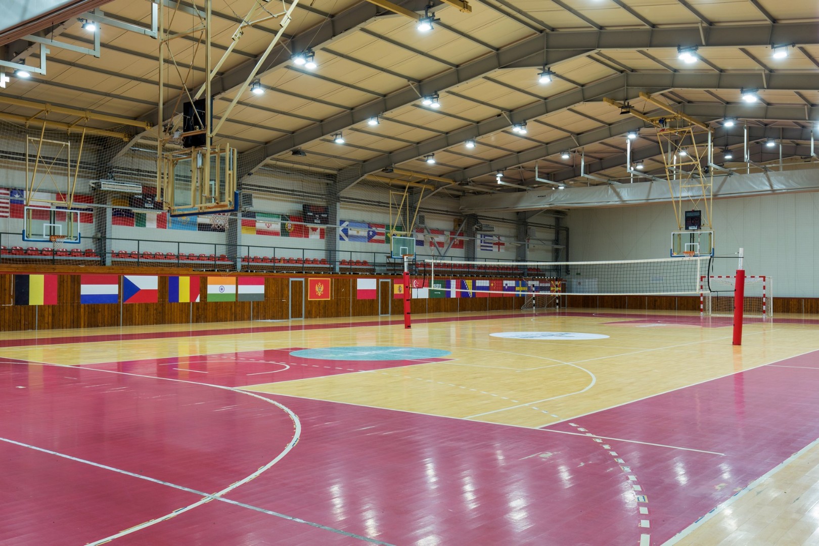Große Indoor-Sporthalle mit Volleyballnetz und Basketballkörben.