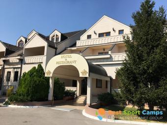 Exterior view of the hotel and restaurant entrance with covered driveway and landscaped greenery.