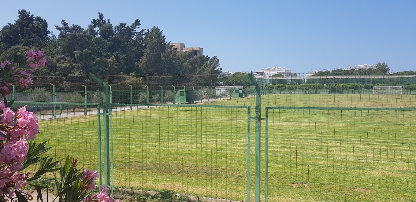 Fenced natural-grass football field with a goal in the distance, suitable for training camp sessions.