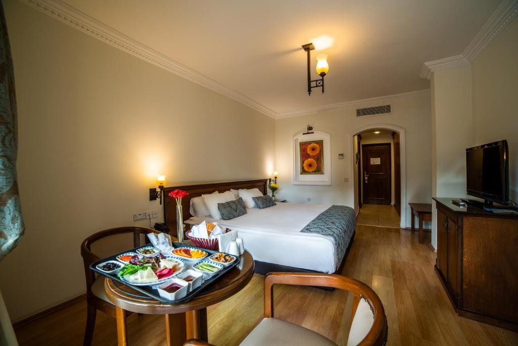 Hotel room with double bed and breakfast tray on a small round table in the foreground.