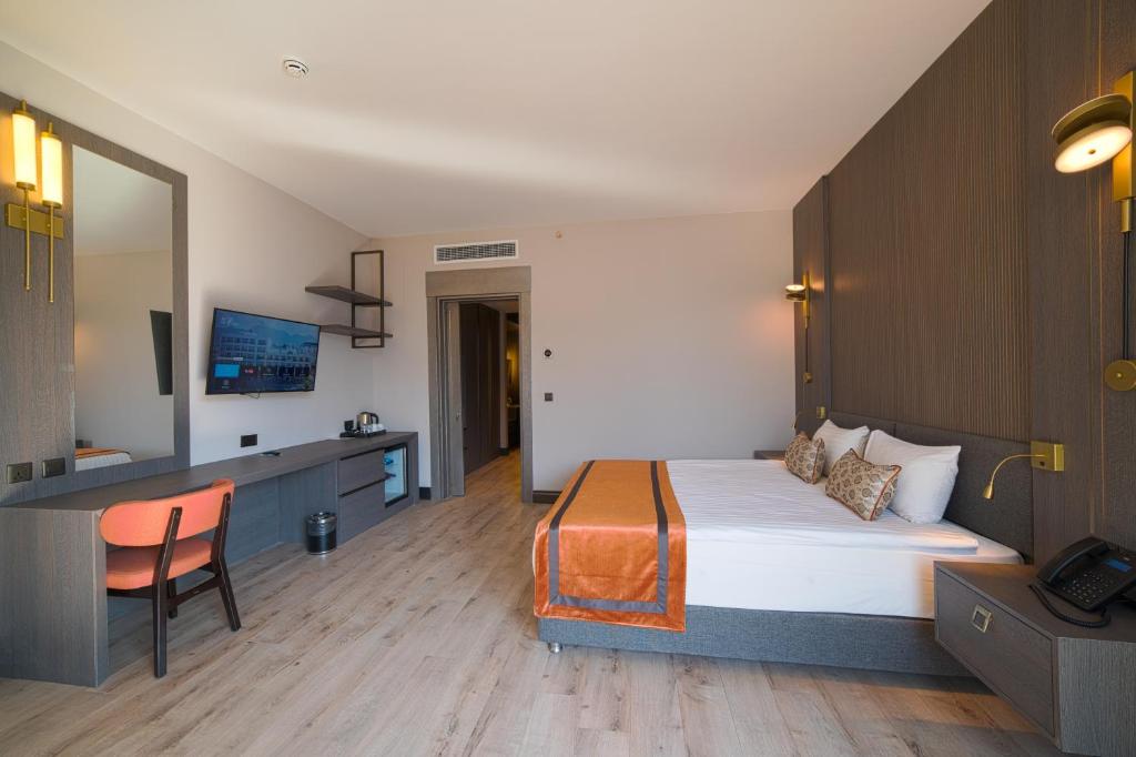 Modern double room with desk, wall-mounted TV, and orange bed runner.