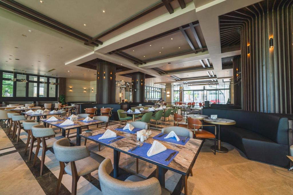 Modern hotel restaurant dining room with set tables, folded napkins, and mixed seating.
