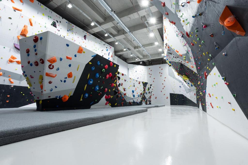 Große Indoor-Boulderhalle mit gepolstertem Boden und überhängenden Wänden.