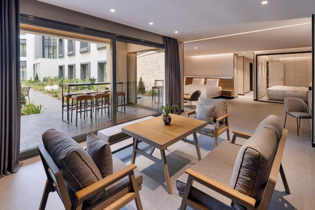 Offene Suite mit Lounge-Bereich und Esstisch, verbunden mit einer Terrasse über große Schiebetüren.