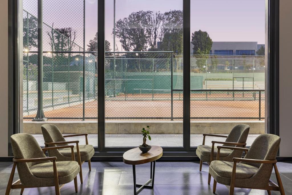 Gemütlicher Lounge-Bereich mit Sesseln und großer Fensterfront mit Blick auf die Tennisplätze.