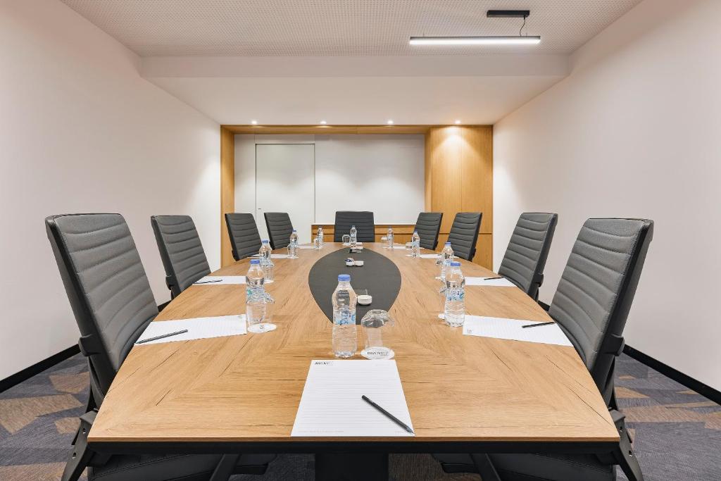 Konferenzraum mit ovalem Tisch, Notizblöcken und Wasserflaschen für ein Meeting.
