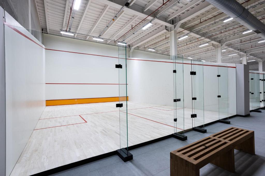 Seitenansicht eines Squash-Courts mit Glasrückwand unter hoher Hallenbeleuchtung.