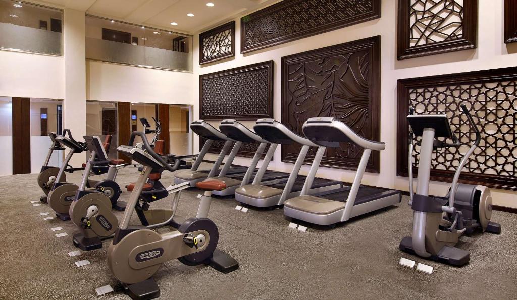 Hotel gym with treadmills and exercise bikes, set against decorative wall panels.