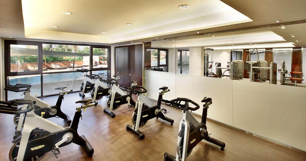 Indoor fitness room with stationary bikes, weight machines, mirrors, and large windows.