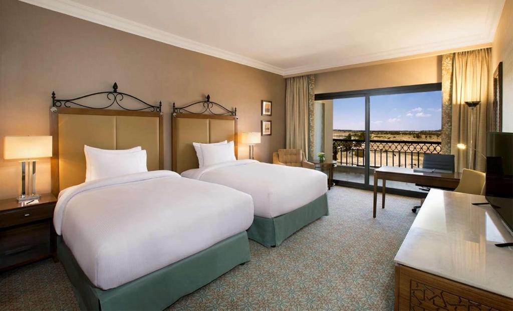 Twin guest room with two beds and a balcony with wide views over the surrounding landscape.