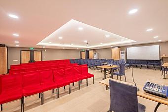 Conference room with classroom seating, projector, sound mixer, and whiteboard for team briefings.