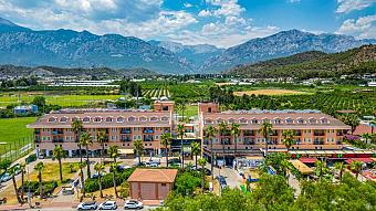Außenansicht des Hotelgebäudes mit Palmen und Bergen im Hintergrund.