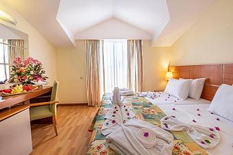 Loft-style hotel room with double bed, desk, and tall window with curtains.