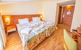 Twin room with two single beds, bedside lamps, desk, and wood flooring.