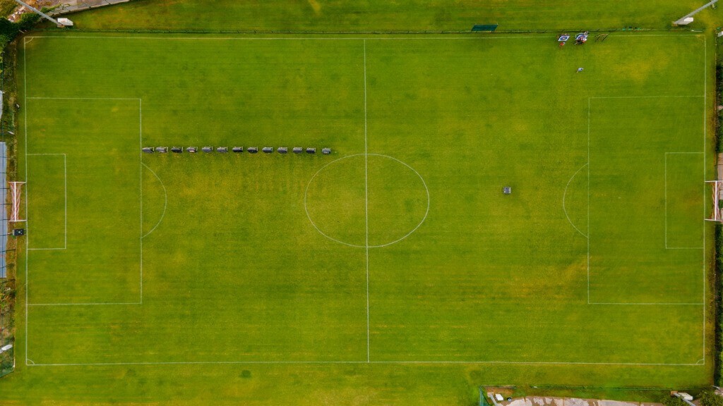 Vue aérienne d'un terrain de football en gazon naturel grandeur nature avec buts et rond central.