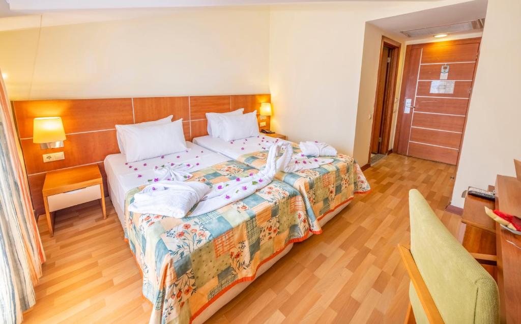 Chambre twin avec deux lits simples, lampes de chevet, bureau et parquet.